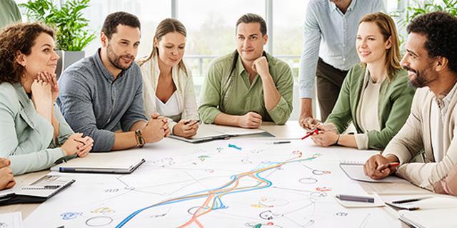 Business owners reviewing a marked growth roadmap around a meeting table in a bright Surrey office